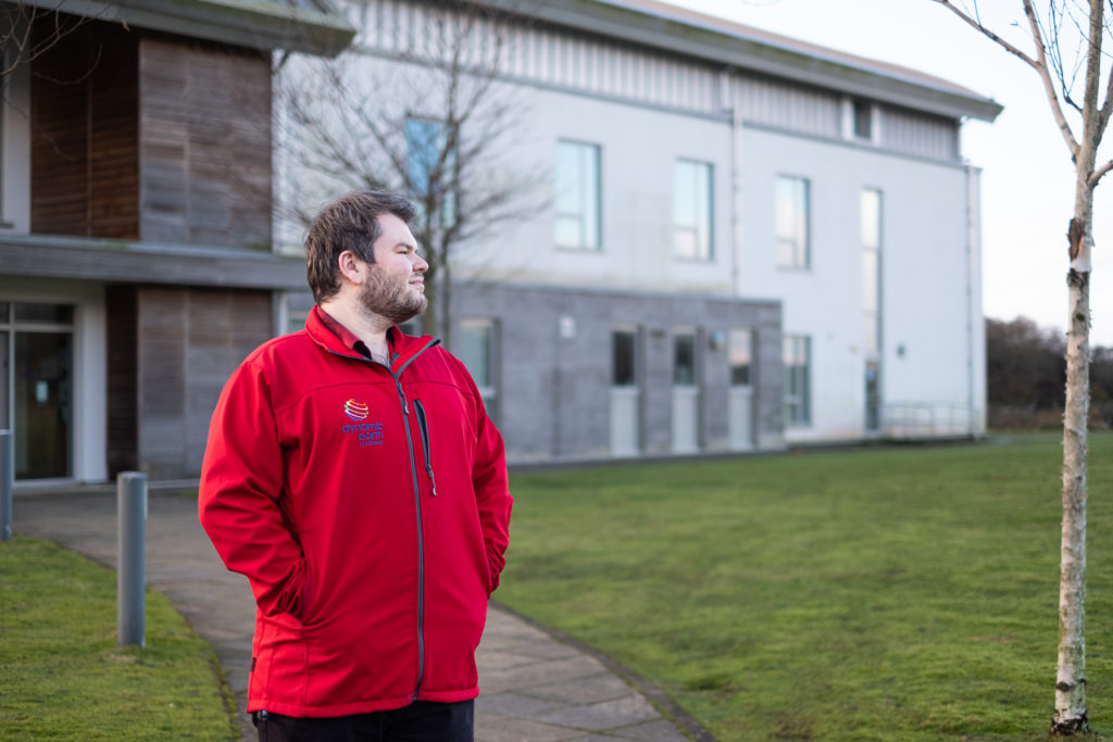 2017 SAMS UHI Alumni Blair Watson stands outside looking out to sea in front of the Sheina Marshall Building at the SAMS UHI Campus.