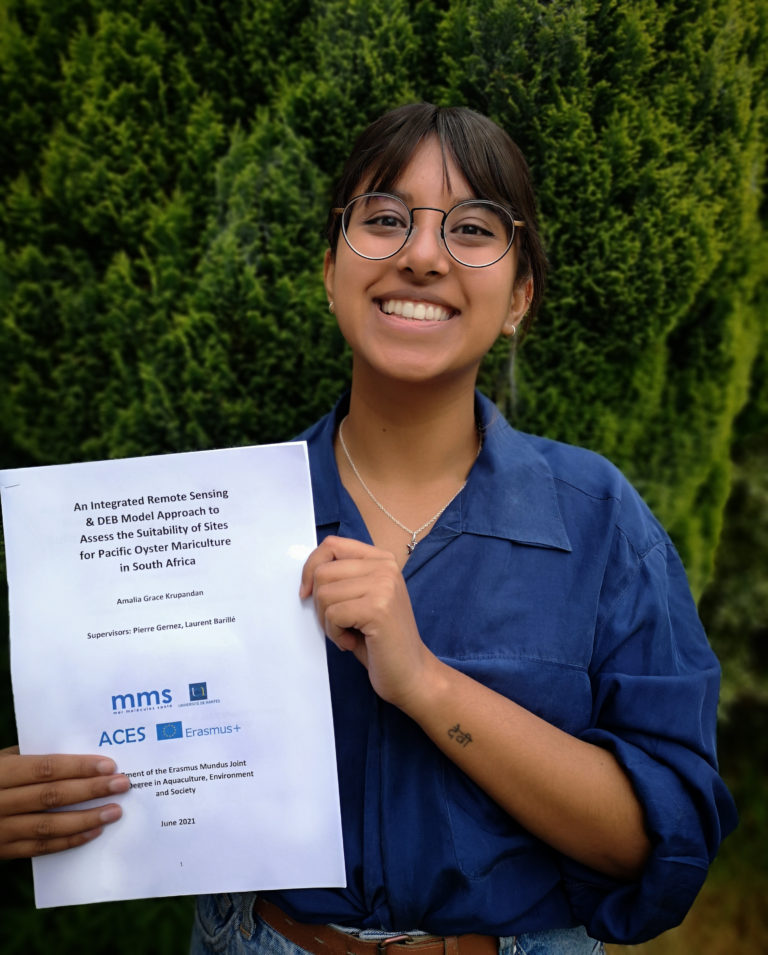 Picture of a very smiley Amalia holding her printed dissertation.